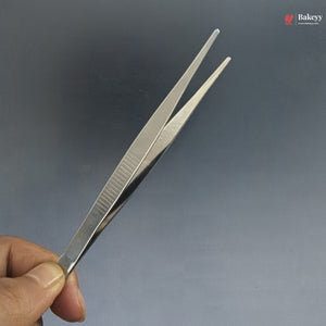 Metal tweezers held by a hand against a gray background