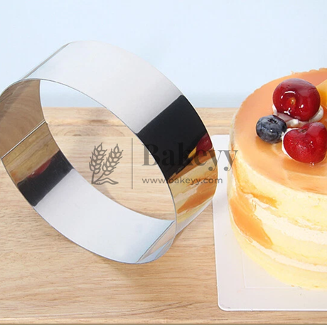Cake server with a wooden handle and metal blade next to a decorated cake on a wooden board.