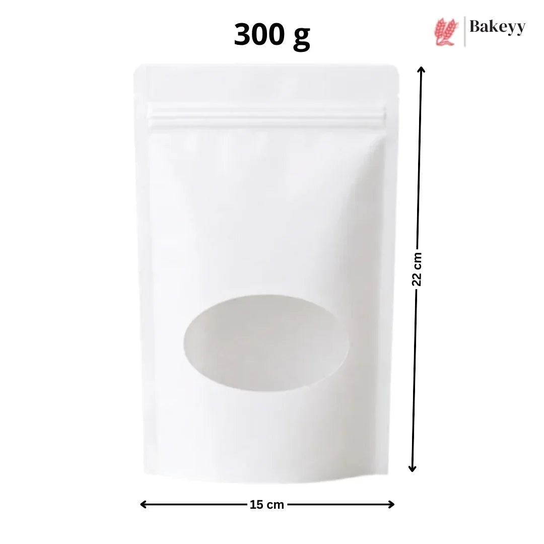 A white stand-up pouch packaging with a die-cut oval window, shown with dimension lines indicating 15 cm width and 22 cm height, with '300 g' text at the top and a Bakeyy logo in the upper right.