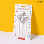 Three silver heart-shaped candles in packaging with 'Happy Birthday' text on a yellow background