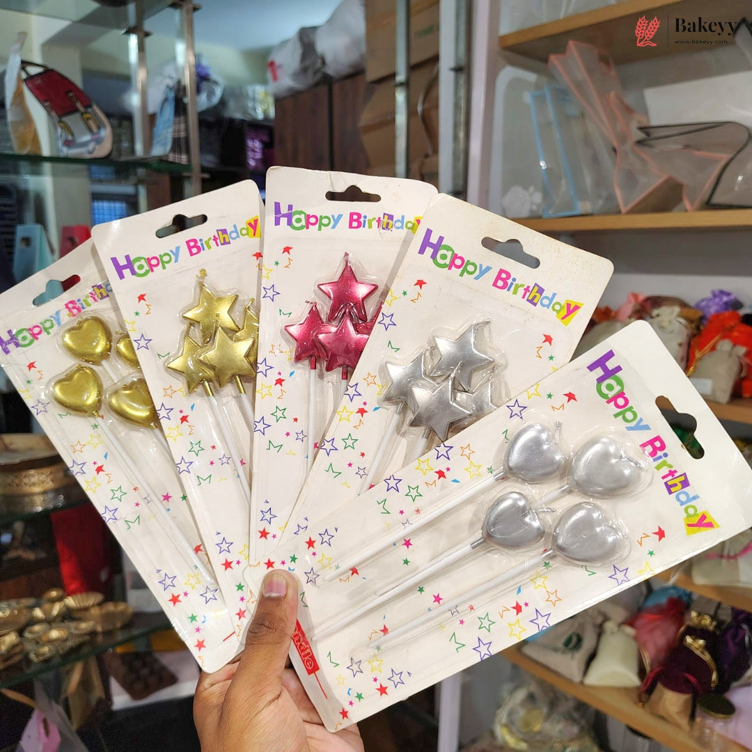Hand holding multiple packages of birthday candles with stars and hearts on a blurred background