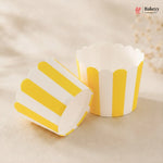 Yellow and white striped cupcake liners on a beige background