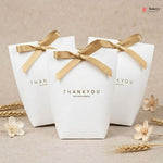 Three white gift boxes with gold ribbons and 'THANKYOU' text on a beige background.