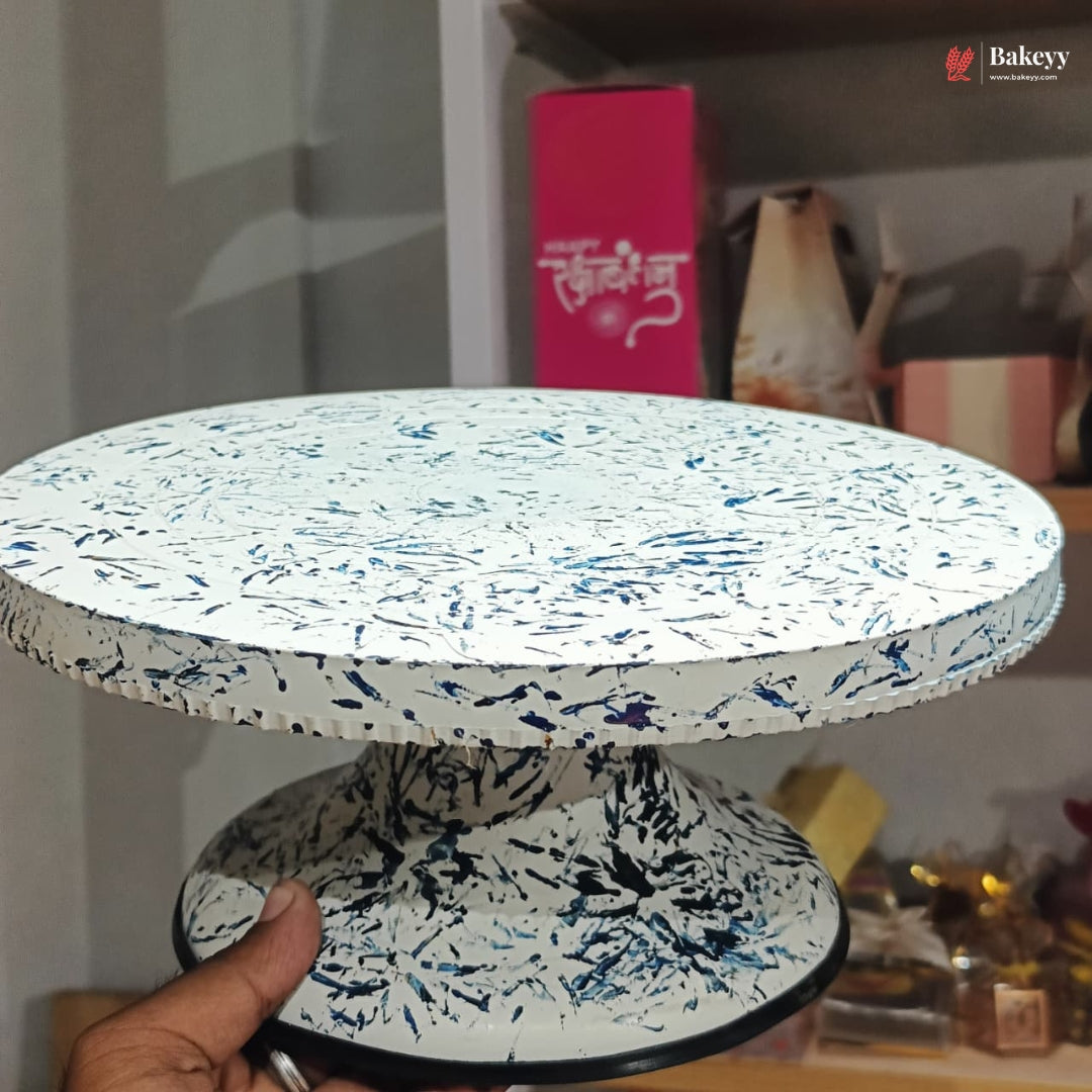 Speckled patterned cake stand held by a hand with a blurred background