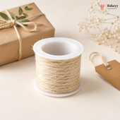 Spool of twine on a white surface with a gift box and decorative elements.