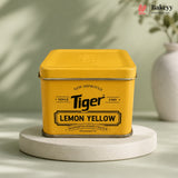 A yellow metal tin of Tiger Lemon Yellow synthetic food colour, displayed on a round white pedestal against a soft green background with a decorative vase in the distance.