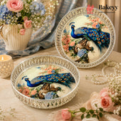 Two round silver metal trays with ornate lace-like rims and printed peacock and floral designs, styled on a table with flowers, a candle, pearls, and a Bakeyy watermark.