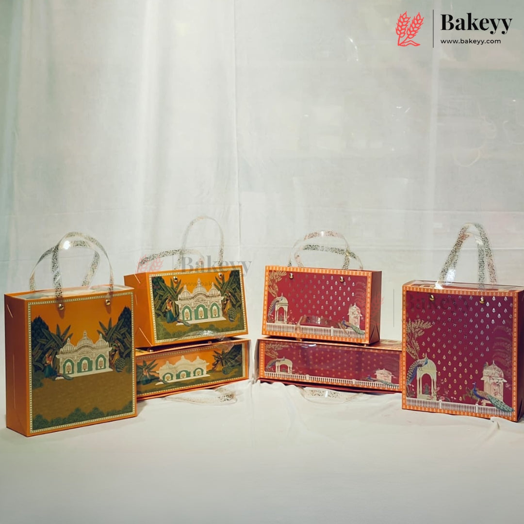 Six decorative gift boxes and packaging bags from Bakeyy arranged on a white surface against a white curtain backdrop. The boxes feature traditional architectural illustrations in orange, green, and red tones, with clear plastic handles.