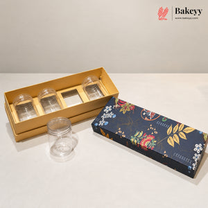 A set of clear plastic storage jars with screw-top lids, shown alongside their packaging. One gold cardboard tray holds three jars, and another clear jar sits in front.