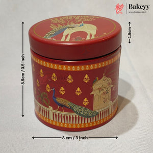 A red cylindrical metal cake tin with a lid, decorated with gold and multicolor peacock and architectural motifs. Black dimension arrows and text indicate a height of 8.