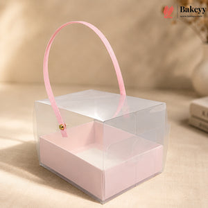 Clear gift box with pink handle and interior on a beige background, featuring the Bakeyy brand.
