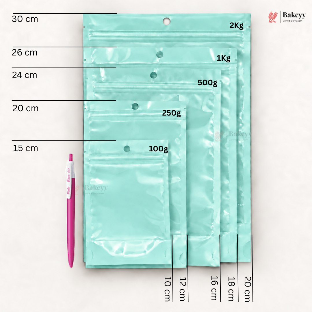 Five mint green resealable zip pouches of different sizes arranged vertically on a white background, with printed size and weight labels (30 cm, 26 cm, 24 cm, 20 cm, 15 cm; 2Kg, 1Kg, 500g, 250g, 100g) and a pink pen for scale. The Bakesy logo appears in the top right.