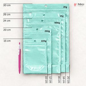 Five mint green resealable zip pouches of different sizes arranged vertically on a white background, with printed size and weight labels (30 cm, 26 cm, 24 cm, 20 cm, 15 cm; 2Kg, 1Kg, 500g, 250g, 100g) and a pink pen for scale. The Bakesy logo appears in the top right.