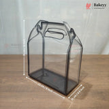 A clear plastic bakery gift bag or container with a handle, shown on a wooden surface with overlaid dimension lines and text indicating 23 cm by 23 cm by 11 cm.