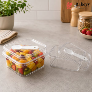 Two clear plastic food storage containers with lids on a countertop, one filled with colorful fruit and one empty, each with a small white spoon inside. A Bakeey logo appears in the top right corner.