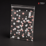 Clear plastic bag with pink and white floral pattern on a black background, featuring the brand 'Bakeyy'.