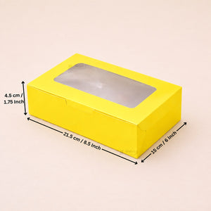 A bright yellow rectangular cardboard box with a clear plastic window on top, shown with black dimension arrows and text indicating measurements of 21.5 cm length, 15 cm width, and 4.