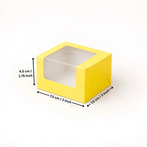 Yellow square box with a clear plastic window on top, shown with dimension arrows and text indicating measurements of 7.5 cm by 7.