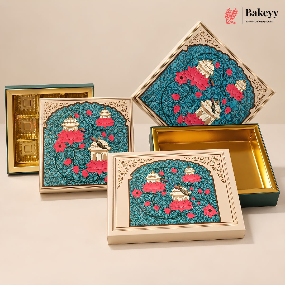 A set of decorative rectangular cake boxes with cream-colored outer panels and teal inner linings, featuring an illustrated floral and bird motif. Several boxes are shown open and closed on a clean off-white studio background, with a Bakeyy logo in the top right corner.