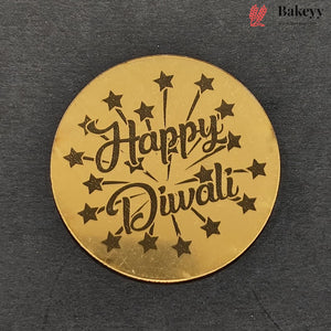 A round gold-colored metal Diwali decoration featuring the words 'Happy Diwali' in black cursive script, surrounded by black stars and sparkles, displayed on a dark textured background.