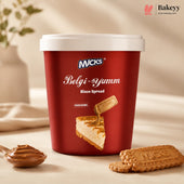A red tub of Micks Belgi-Yumm Bisco Spread with a white lid, styled on a beige surface with a spoonful of spread and two biscuit cookies in the foreground.