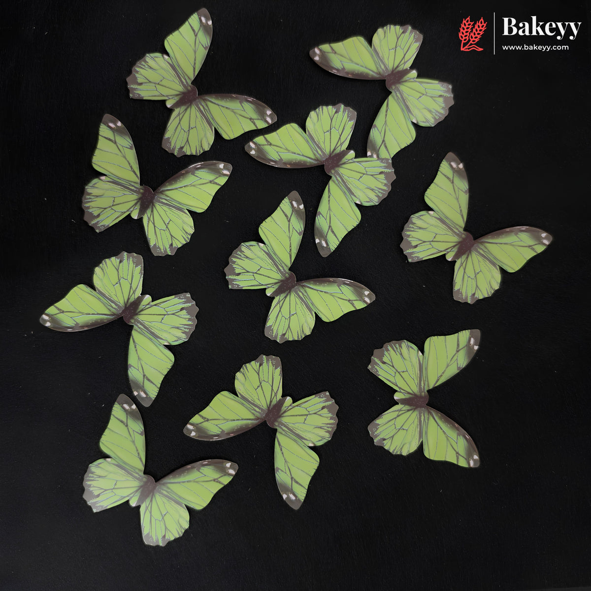 Ten butterfly-shaped cake toppers in light green with dark purple veins and tips, arranged on a black background. The Bakeey brand logo is visible in the top right corner.