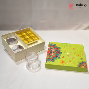 A bakery gift set display featuring an open cream-colored box with two clear glass jars and a tray of gold square chocolates, alongside a closed lime green decorative box with a mandala pattern. The Bakeyy brand logo is visible in the top right corner.