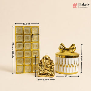Three gold and white decorative items shown with dimension arrows and labels: a rectangular foil packet measuring 13.5 cm by 28 cm, a small Ganesha figurine 5.