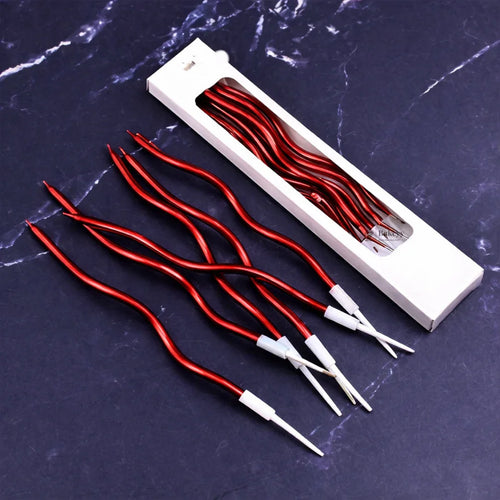 Red wavy spiral birthday cake candles with holders from Bakeyy, displayed on a dark surface.