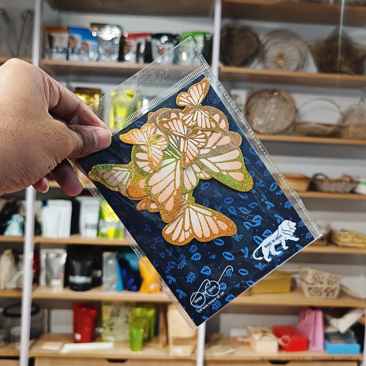 Hand holding a card with butterfly design in front of a store shelf.