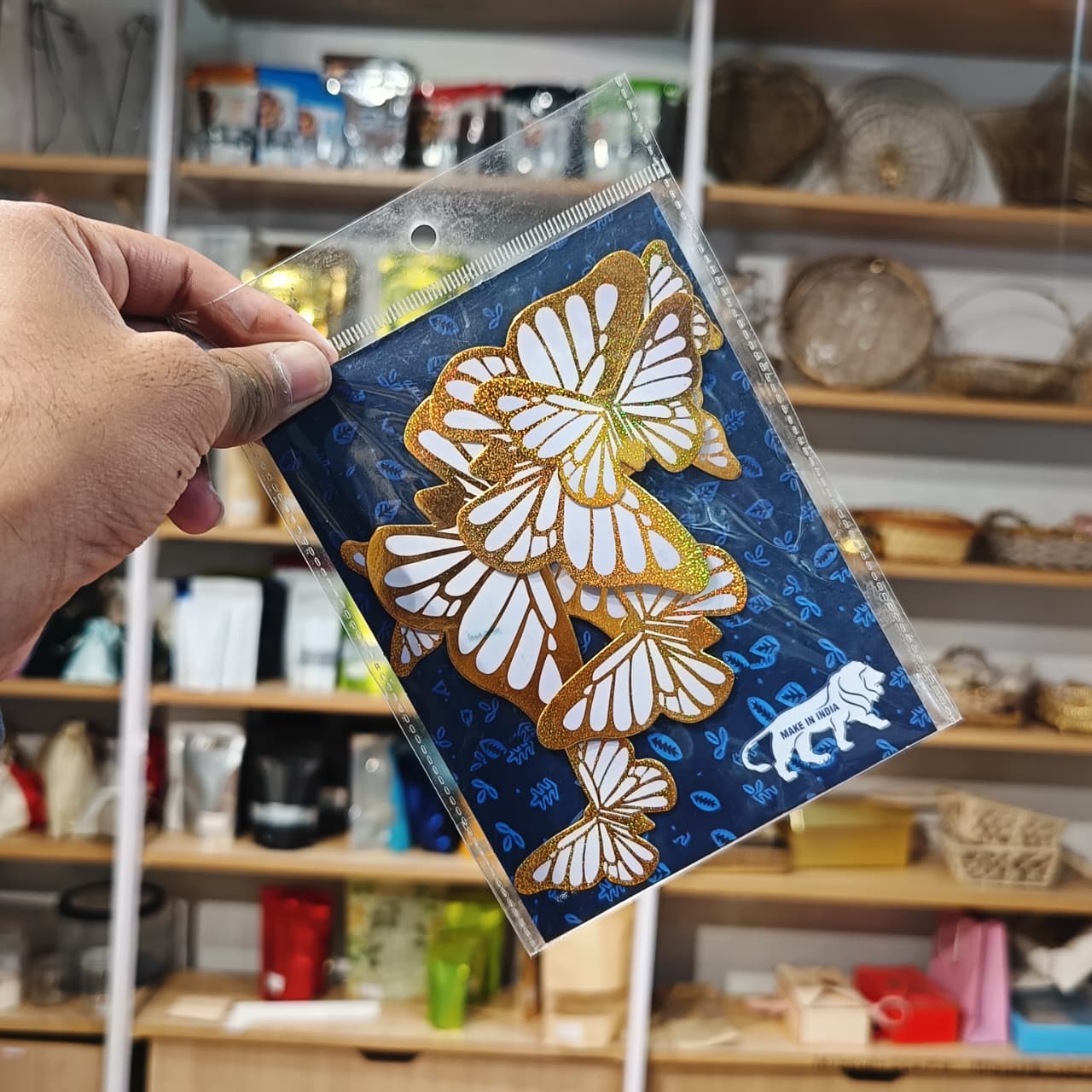 Hand holding a card with butterfly design in front of a store shelf