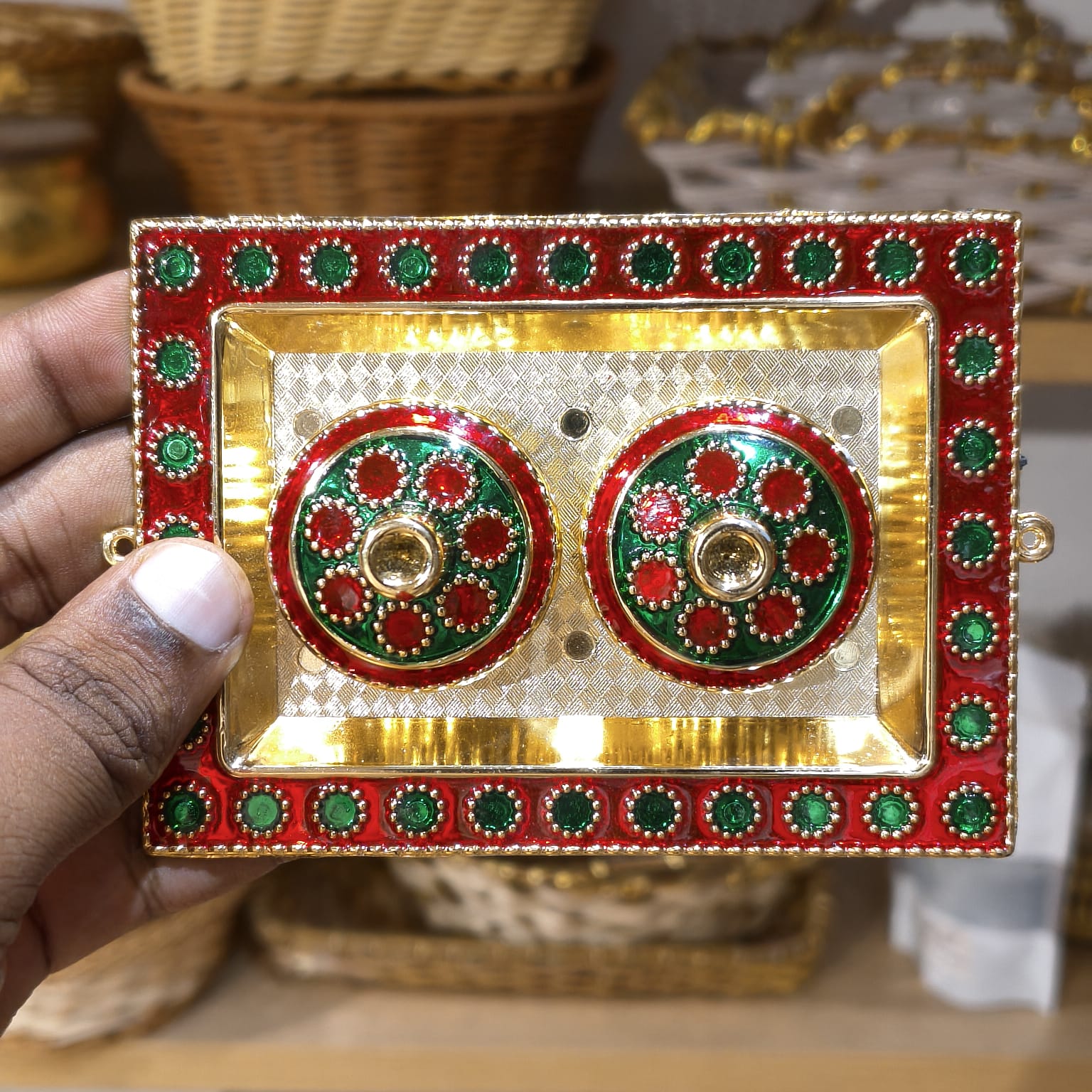 Decorative red and gold box with green accents held by a hand.