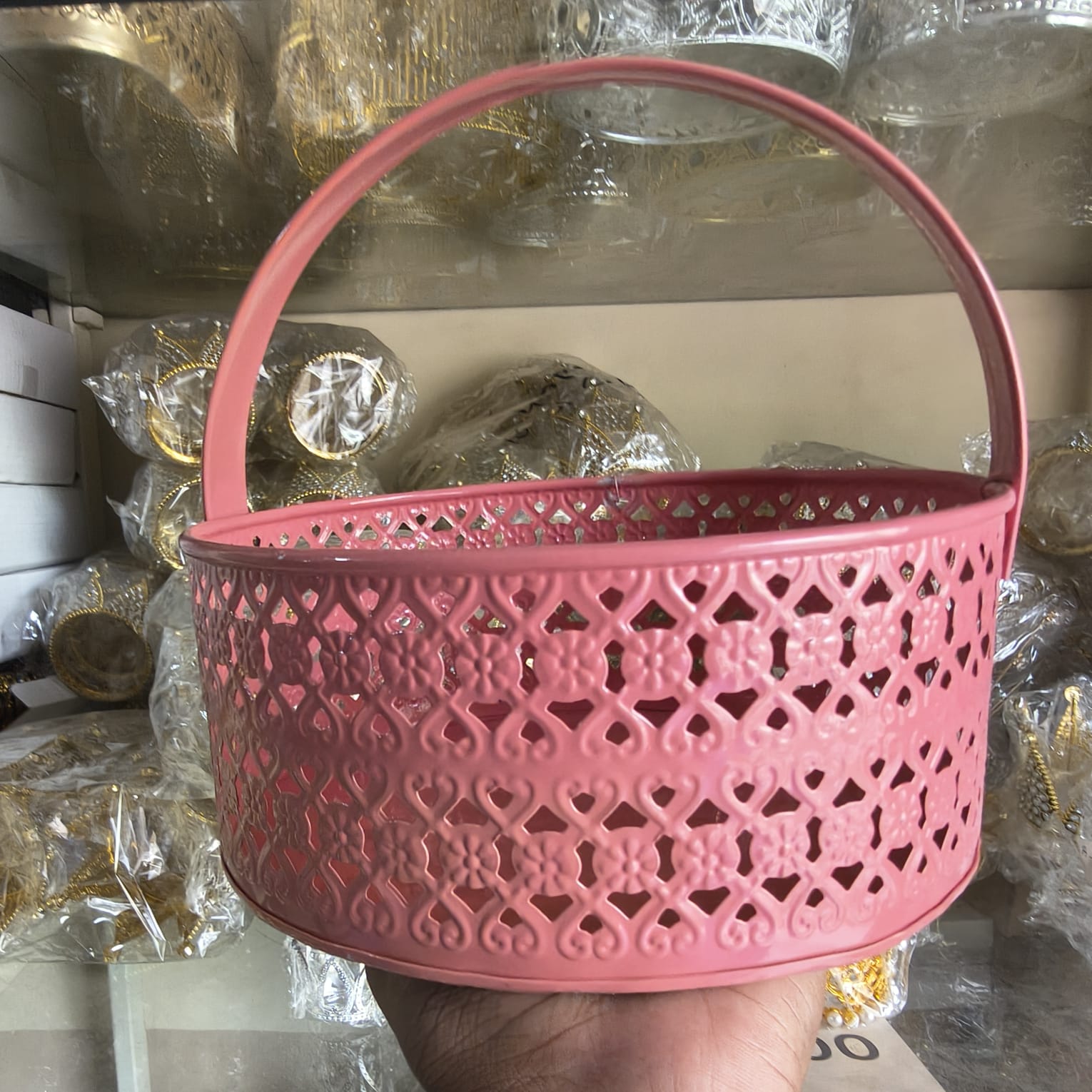 Pink decorative basket with intricate patterns held in front of a blurred background