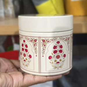 Hand holding a decorative ceramic container with floral patterns
