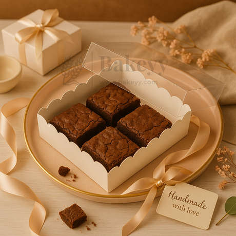 Box of brownies with a decorative ribbon on a wooden surface, accompanied by a gift box and tag.