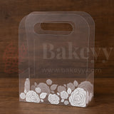 Clear cake box with floral design on a wooden background, featuring the brand 'Bakeyy'.