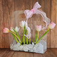 Clear plastic bag with pink and white tulips and a pink bow on a wooden background
