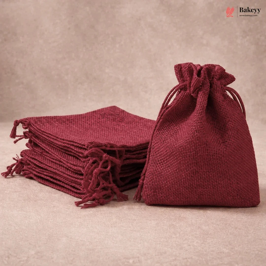 A stack of and one single burgundy jute drawstring gift bags on a neutral beige background. The brand logo 'Bakeyy' is visible in the top right corner.