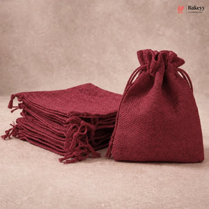A stack of and one single burgundy jute drawstring gift bags on a neutral beige background. The brand logo 'Bakeyy' is visible in the top right corner.