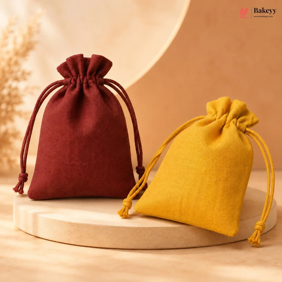 Two small drawstring pouches, one in deep burgundy and one in mustard yellow, displayed on a round wooden pedestal against a warm beige background. The Bakeey brand logo is visible in the top right corner.