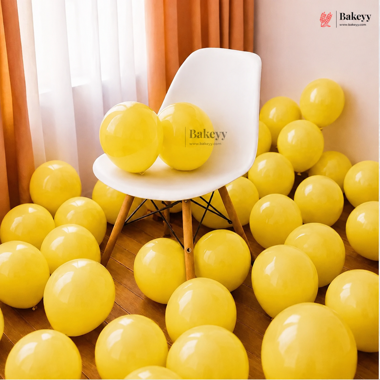 Yellow party balloons filling a room with a white molded chair in the center, sheer curtains, and a warm peach wall. A Bakeey logo watermark is visible on the chair and in the top right corner.