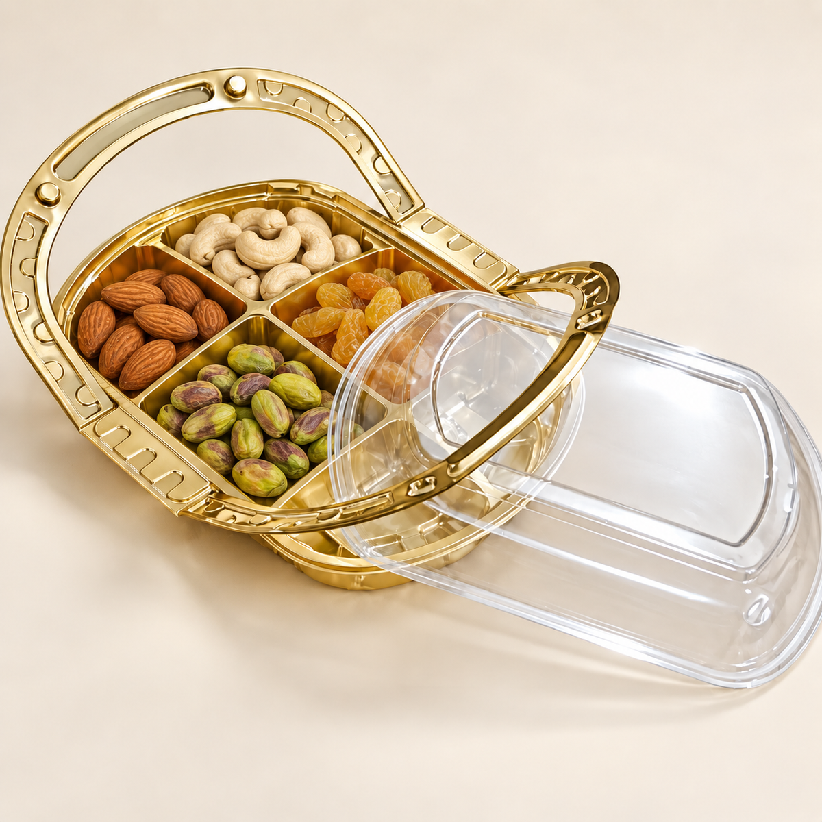 A gold metal divided snack basket with a clear plastic lid, shown open with compartments filled with almonds, cashews, pistachios, and raisins on a light beige background.