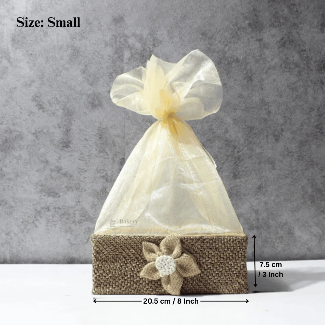 Small jute net hamper basket with cream organza wrap and flower accent, ideal for gift packaging from Bakeyy.com.
