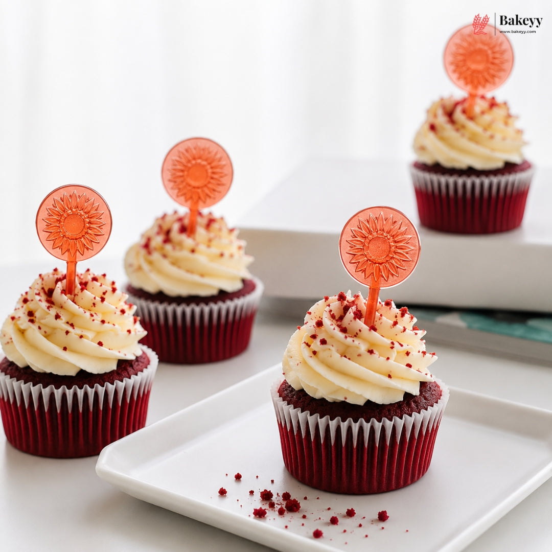 Red velvet cupcakes with white frosting and decorative picks on a white plate, with 'Bakey' branding.