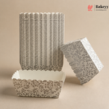 Decorative paper cupcake liners with a scalloped edge and intricate pattern on a beige background, branded 'Bakeyy'.