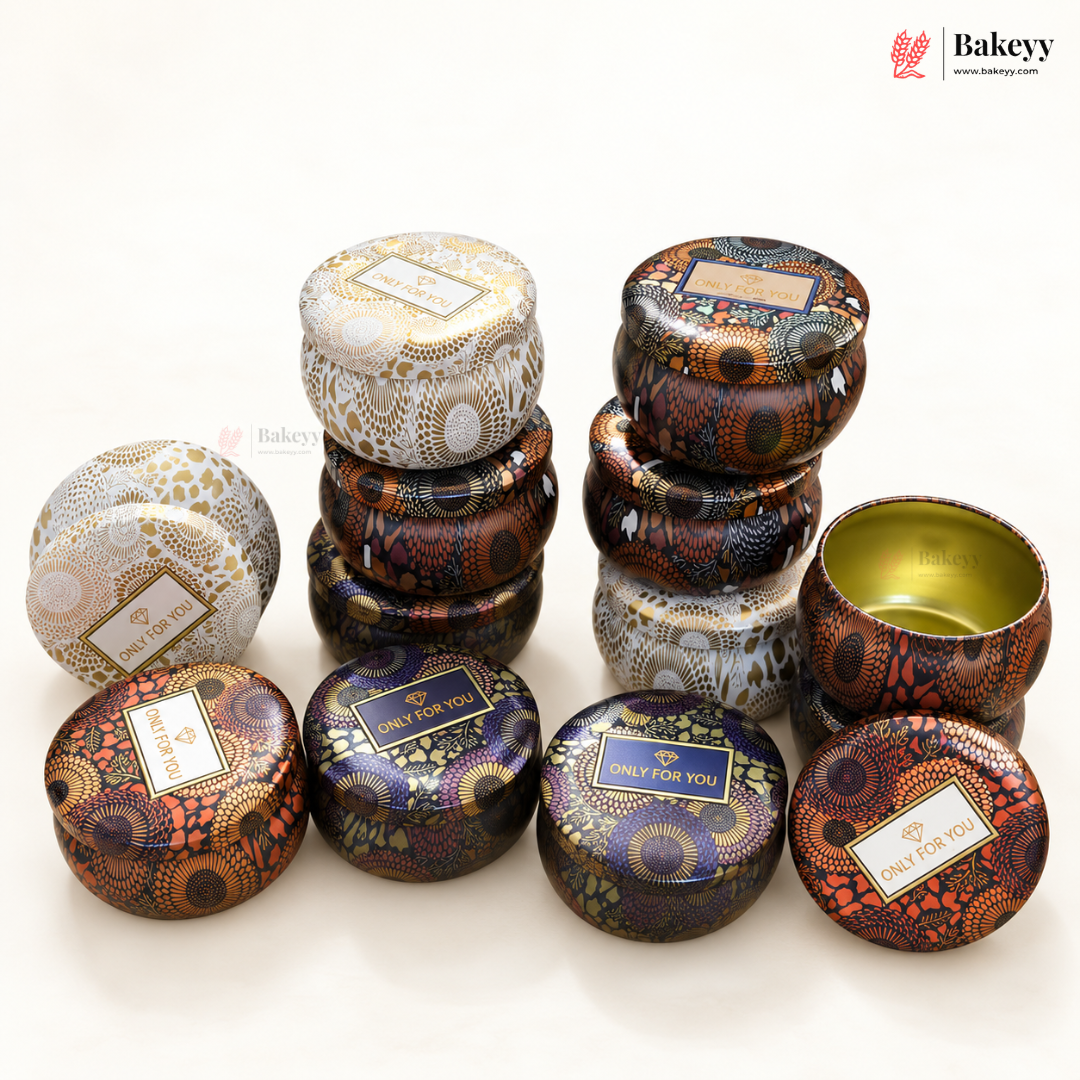 A group of round metal tin containers with decorative patterns, shown on a clean white background. Some tins are stacked, and one open tin is displayed to show the gold interior.