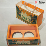An orange bakery gift box with a clear plastic window and decorative printed illustration of a palace and elephants, shown both open and closed on a light gray background. The Bakeyy logo is visible in the top right corner.